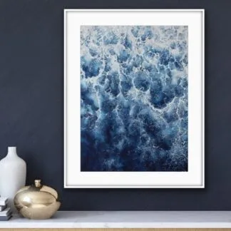 Framed abstract ocean wave painting ‘Deep Blue Sea’ above the commode in a modern living room, featuring rich blues and foam for an elegant touch.