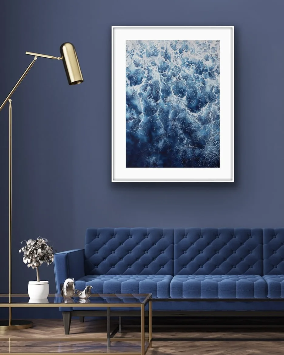 ‘Deep Blue Sea’ framed above a minimalist sofa in a modern living room, highlighting the textured ocean waves and foam details.