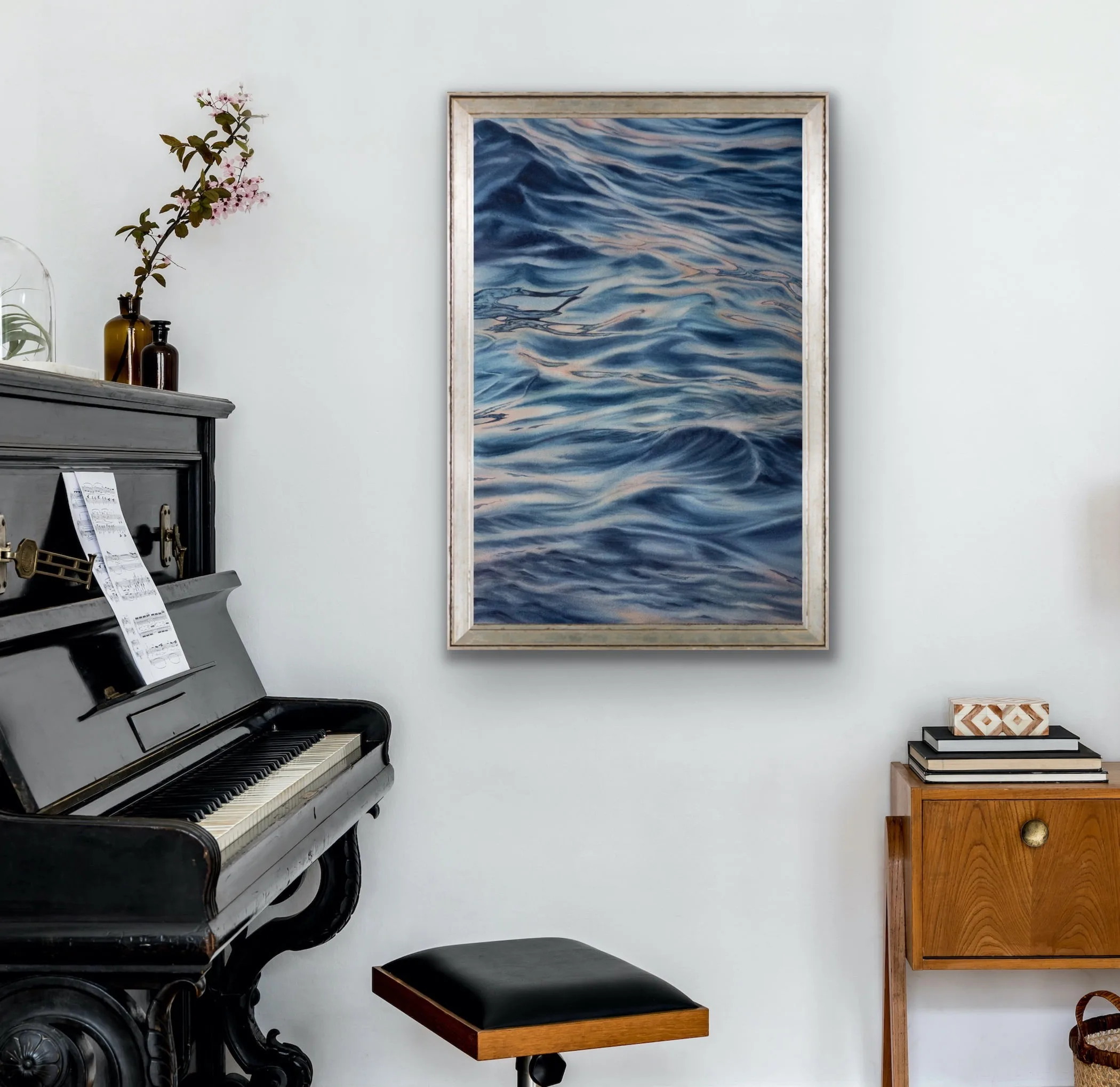 "Evening Mood" watercolor seascape framed above a piano in a living room, blending soft blues and grays to create a peaceful ocean scene that complements the tranquil ambiance of the space