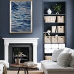 "Evening Mood" framed watercolor seascape hanging above the fireplace in a coastal living room, with soft blues and grays evoking a calm ocean atmosphere, enhancing the serene ambiance of the space.