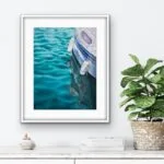 "Summer Memories" watercolor painting framed above a shelf in a coastal-inspired room, featuring a yacht and calm sea, adding a tranquil ocean touch to the space.