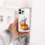 Stylish clear iPhone case showcasing a playful watercolor pyramid of pumpkins, ideal for seasonal and festive style.