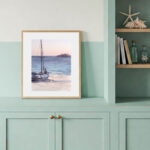 Original watercolor seascape with peaceful sunset and sailboat featured in cozy coastal living room, beach house wall art, nautical home decor, tranquil ocean painting gift for sea lovers, marine-style living space design.