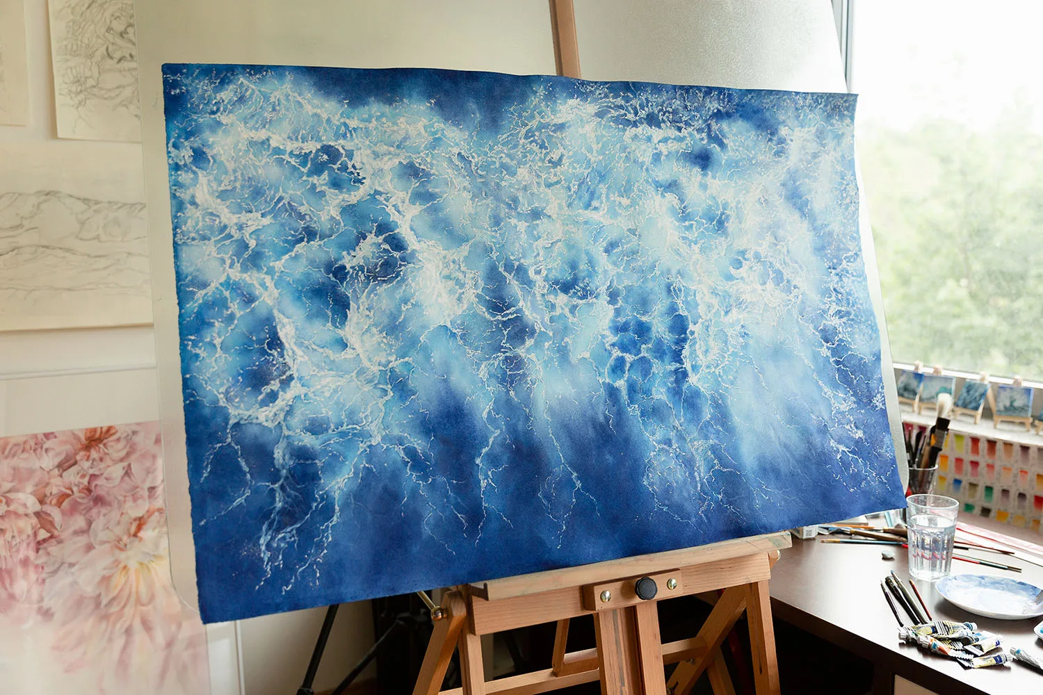 Partially abstract painting 'Ocean Blues' displayed on an easel in the studio, revealing its intricate ocean wave textures and serene color palette during the creation process.