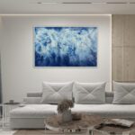 Framed 'Ocean Blues' watercolor painting in a modern living room above the sofa.