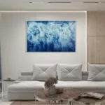 Framed 'Ocean Blues' watercolor painting in a modern living room above the sofa.