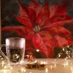 Red poinsettia soft pastel painting displayed in the artist's studio with Christmas decor, creating a festive and vibrant atmosphere in the space.