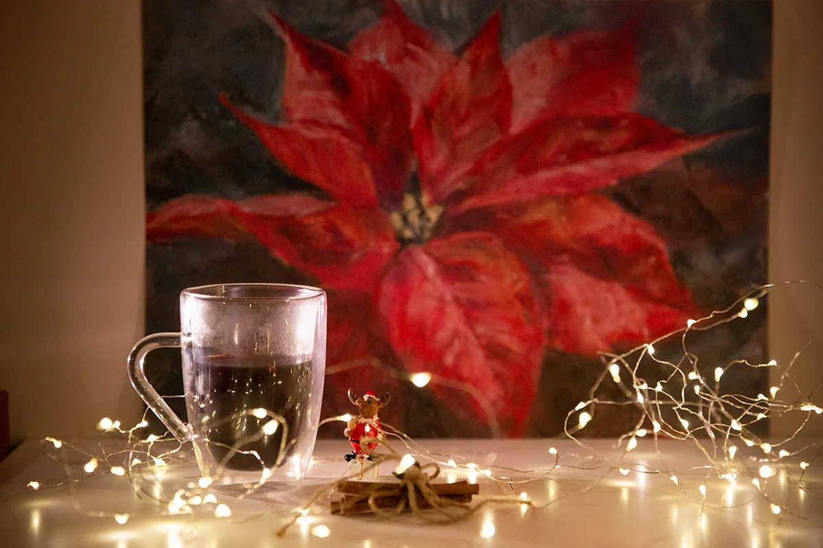 Red poinsettia soft pastel painting displayed in the artist's studio with Christmas decor, creating a festive and vibrant atmosphere in the space.