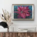 Red poinsettia soft pastel painting above a dresser in a cozy room, adding a vibrant and festive touch to the space.