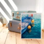 Framed ‘Blue and Yellow Boat’ in a creative studio, adding a peaceful nautical vibe with its tranquil boat and calming water reflections.