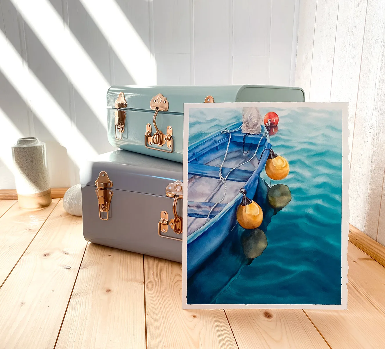 Framed ‘Blue and Yellow Boat’ in a creative studio, adding a peaceful nautical vibe with its tranquil boat and calming water reflections.