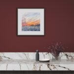 Framed ‘Sunset by the Sea’ in a minimalist interior, featuring the vibrant sunset over the ocean to create a relaxing ambiance.