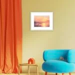 Framed ‘Golden Sunset’ in a modern living room, bringing a vibrant sunset sky and ocean waves to the space.