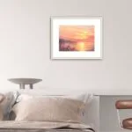 Framed ‘Golden Sunset’ in a cozy bedroom, creating a tranquil ambiance with its glowing sunset over the ocean.