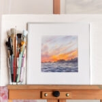 Framed watercolor painting 'Sunset by the Sea' – stormy deep blue ocean waves under a glowing sunset sky, expressive seascape wall art for coastal home decor.