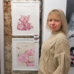 Kateryna Nazarenko standing next to her 'Pink Opuntia Cactus' watercolor painting at an exhibition, showcasing the delicate pink tones and botanical details in a serene, modern style.