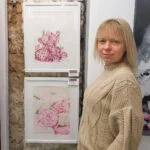 Kateryna Nazarenko standing next to her 'Pink Opuntia Cactus' watercolor painting at an exhibition, showcasing the delicate pink tones and botanical details in a serene, modern style.