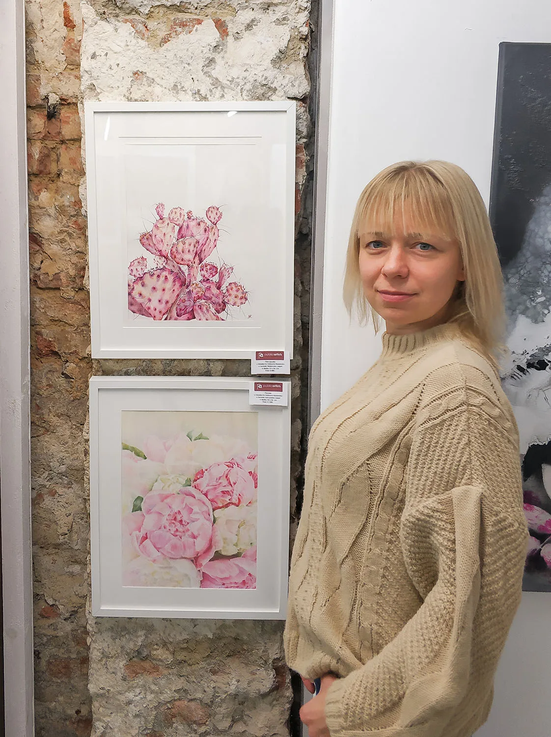 Kateryna Nazarenko standing next to her 'Pink Opuntia Cactus' watercolor painting at an exhibition, showcasing the delicate pink tones and botanical details in a serene, modern style.