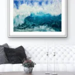 ‘Through the Light’ original watercolor painting above a sofa in a modern living room, showcasing powerful ocean waves with blue and turquoise hues, adding a calming yet dynamic touch to the coastal-themed interior design.