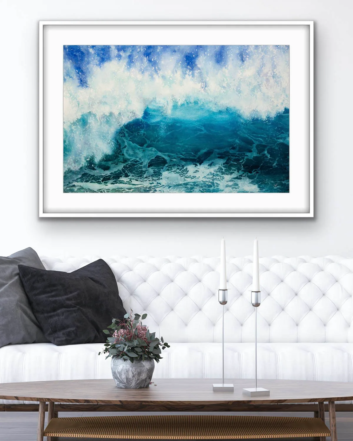 ‘Through the Light’ original watercolor painting above a sofa in a modern living room, showcasing powerful ocean waves with blue and turquoise hues, adding a calming yet dynamic touch to the coastal-themed interior design.