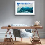 ‘Through the Light’ watercolor painting above the desk in a home office, showcasing crashing waves in shades of deep blue, turquoise, and white foam, bringing energy and serenity to the workspace with its vibrant ocean scene.