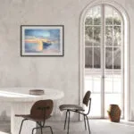Framed "Morning Solitude" painting enhancing a bright dining space with calming sunrise hues over the water.