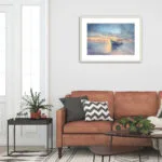 Framed "Morning Solitude" painting above a sofa, complementing the room's coastal-inspired decor.