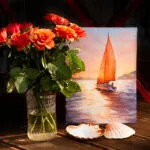 Sailing into the Sunset artwork in an artist’s studio, surrounded by flowers, capturing the warm, dreamy glow of a sunset at sea.