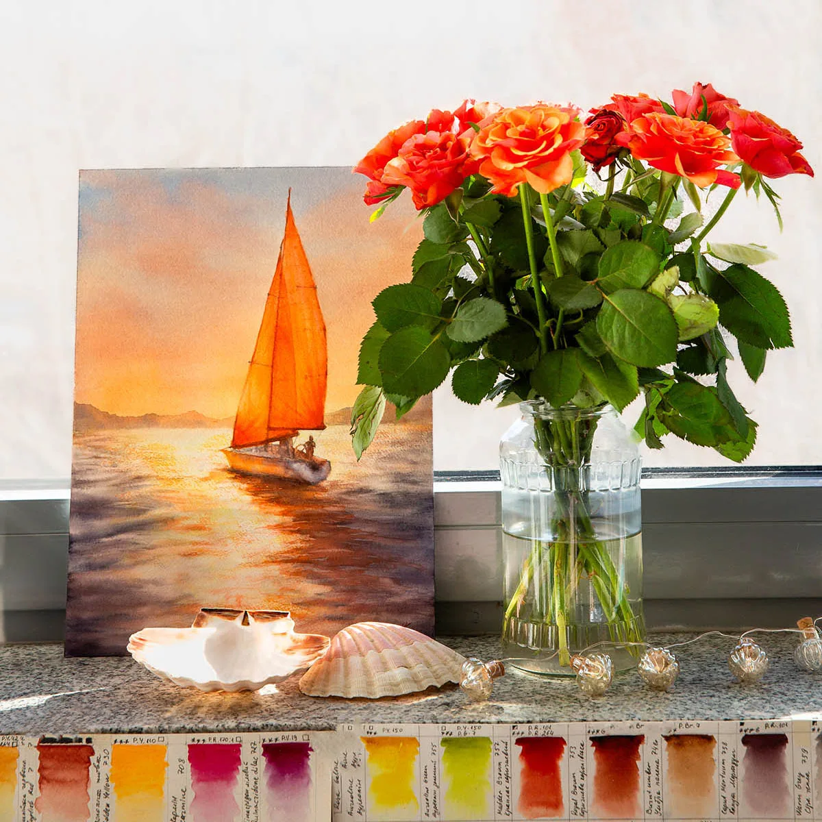 Sailing into the Sunset watercolor painting displayed on a studio window with soft natural light and fresh flowers, enhancing its serene coastal ambiance.