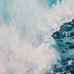 Close-up of spray from crashing ocean wave in shades of white and blue.
