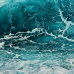 Close-up of a dynamic wave with deep blue and turquoise hues.