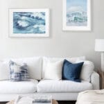 Blue Ocean Whisper watercolor print above sofa in coastal-style living room, abstract ocean wave painting for serene beach-inspired decor.