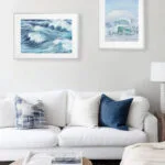 Blue Ocean Whisper watercolor print above sofa in coastal-style living room, abstract ocean wave painting for serene beach-inspired decor.