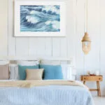 Blue Ocean Whisper framed ocean art above bed, soft wave watercolor painting adding calm marine atmosphere to coastal bedroom decor.