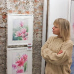 Artist Kateryna Nazarenko presenting her floral watercolor painting Dancing Tulips at an art exhibition, showcasing elegant tulips in delicate hues.