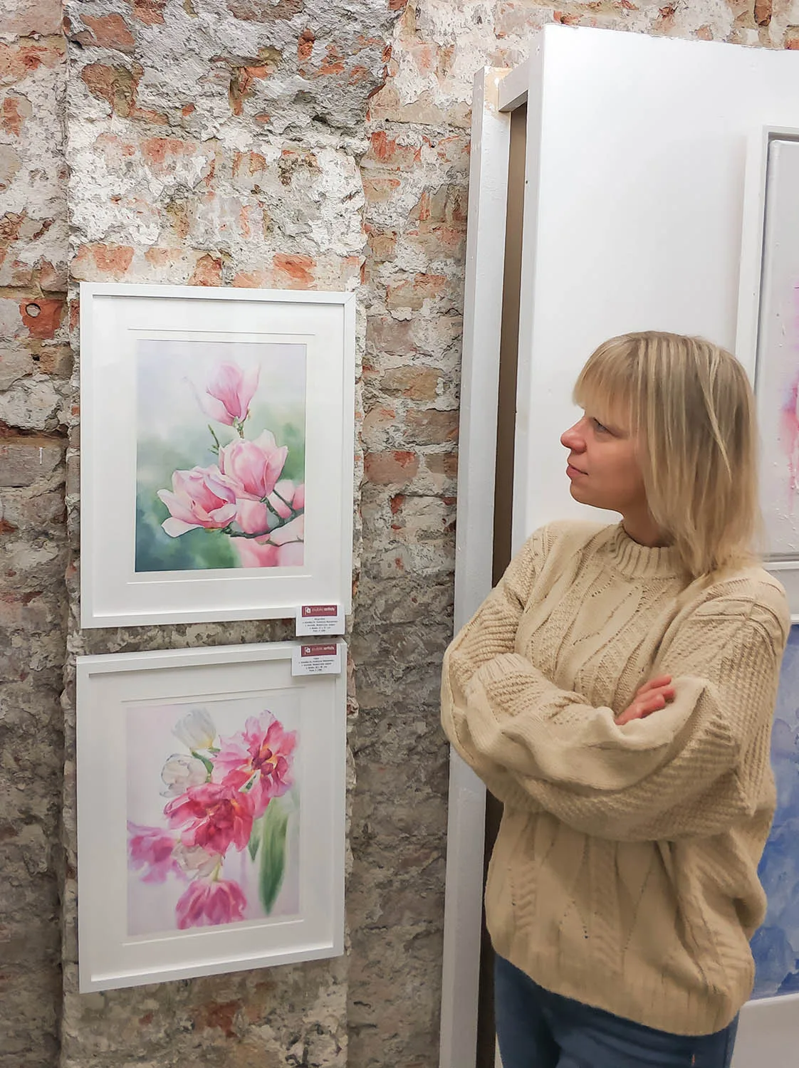 Artist Kateryna Nazarenko presenting her floral watercolor painting Dancing Tulips at an art exhibition, showcasing elegant tulips in delicate hues.