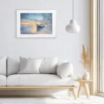 Elegant modern white living room with framed fine art print Morning Solitude, a peaceful watercolor seascape featuring sunrise, calm water, and a resting boat.
