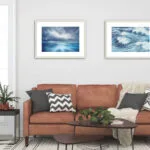 "Where Storm Meets Light" fine art print of a stormy sea watercolor painting displayed above a sofa in the living room. This blue ocean wall art creates a dramatic, serene focal point, enhancing the room with a contemporary, marine-inspired style that blends beautifully with the seating area.