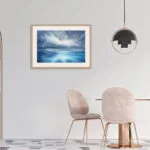 "Where Storm Meets Light" fine art print of a stormy sea watercolor painting displayed in a contemporary dining room. This blue ocean wall art adds a touch of elegance and drama, complementing the modern dining space with a seascape that brings nature's beauty to the table.