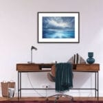 "Where Storm Meets Light" fine art print of a stormy sea watercolor painting displayed in a home office. This blue ocean wall art adds a calming, yet dramatic touch to the workspace, enhancing the modern, coastal-inspired decor with a peaceful seascape focal point.