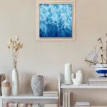 Framed abstract ocean painting "Liquid Energy" displayed in modern interior, blue watercolor artwork adding a coastal and contemporary feel to the space.