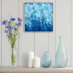 "Liquid Energy" abstract ocean watercolor painting on canvas displayed on a wall, featuring flowing blue sea tones and contemporary coastal decor for a modern interior.