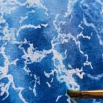 Work in progress of "Liquid Energy" abstract seascape watercolor painting on canvas, with visible brushstrokes and flowing blue pigments illustrating the movement and energy of the sea.