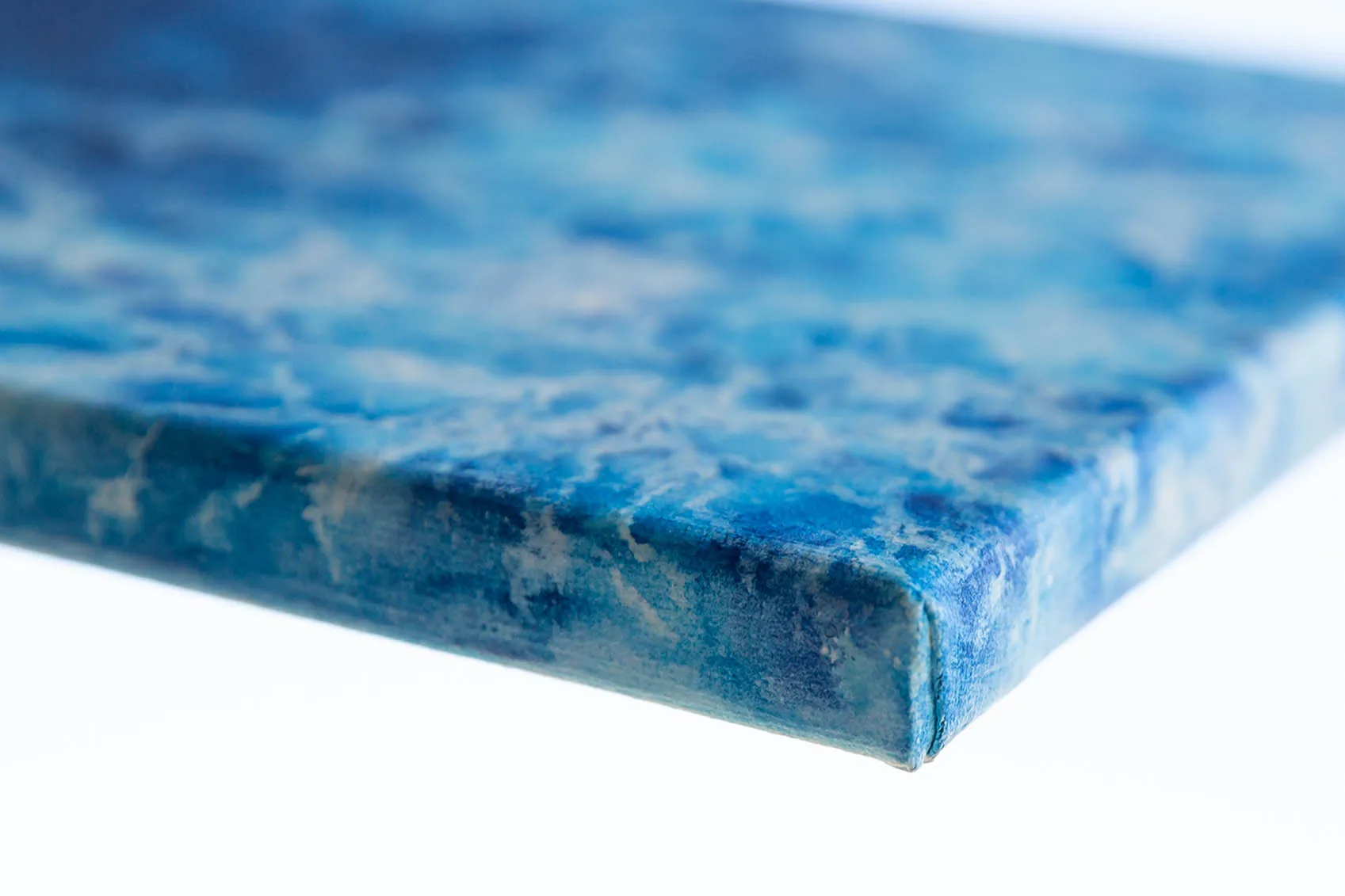 Side view of "Liquid Energy" abstract ocean watercolor painting on canvas, highlighting wrapped edges and textured surface in flowing blue tones.