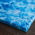 Angled side view of framed "Liquid Energy" blue ocean watercolor artwork, showing modern presentation of canvas and depth of seascape-inspired brushwork.