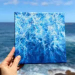 Original abstract ocean watercolor painting titled "Liquid Energy" in dynamic shades of blue, capturing fluid motion of sea water on canvas with light and depth.