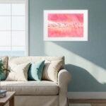 "Pink Lakes of Ukraine" original watercolor art placed above sofa in coastal interior, bringing warmth and natural beauty through soft pinks and salt textures — perfect for beach-themed home styling.