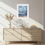 Framed After Dark watercolor seascape painting of ocean horizon and stormy sky, displayed in a modern living room interior