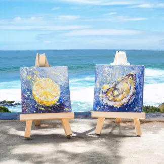 Coastal diptych featuring miniature lemon and oyster acrylic paintings displayed on wooden easels.